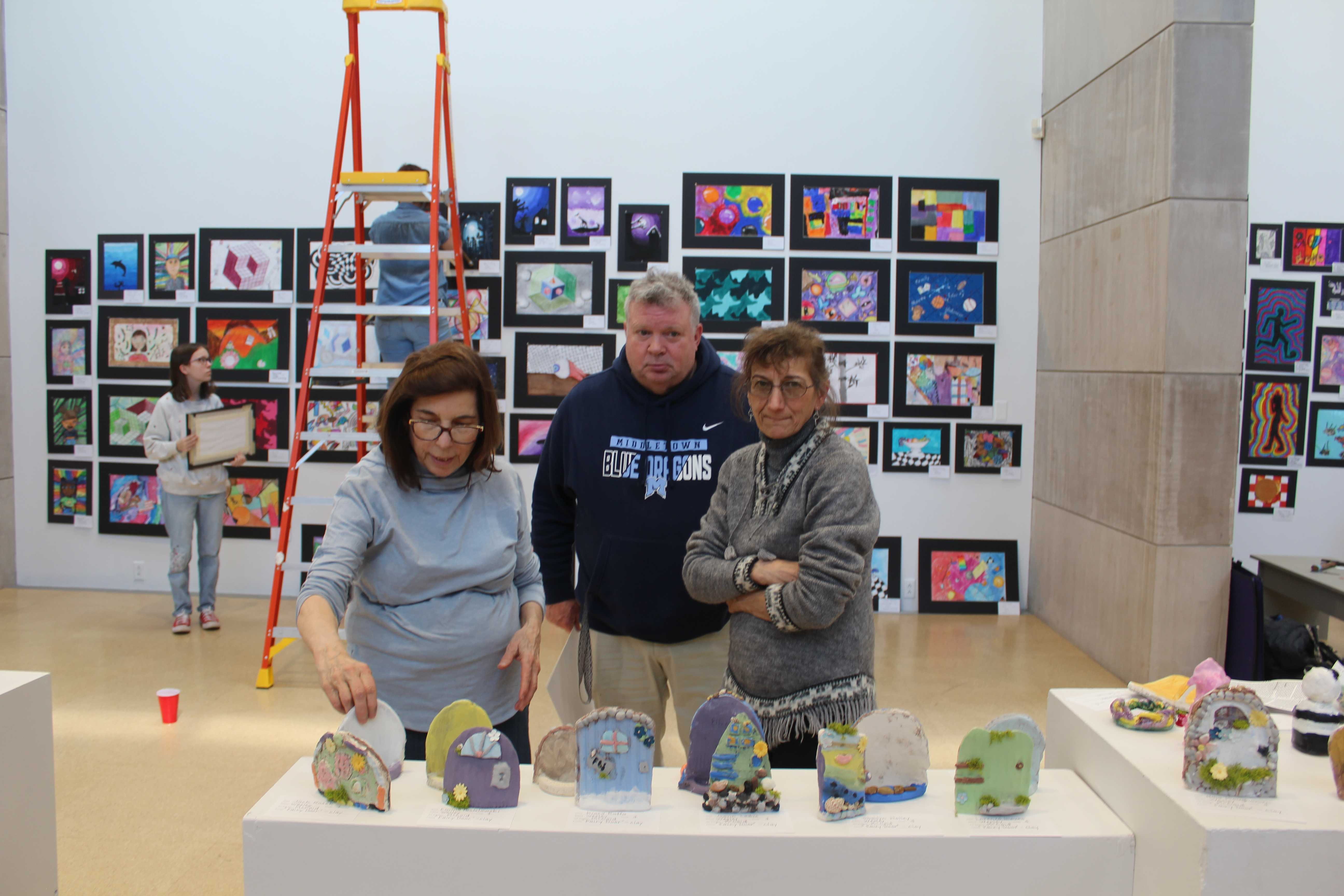 Staff members are seen viewing some of the pieces of artwork on display for the upcoming art show